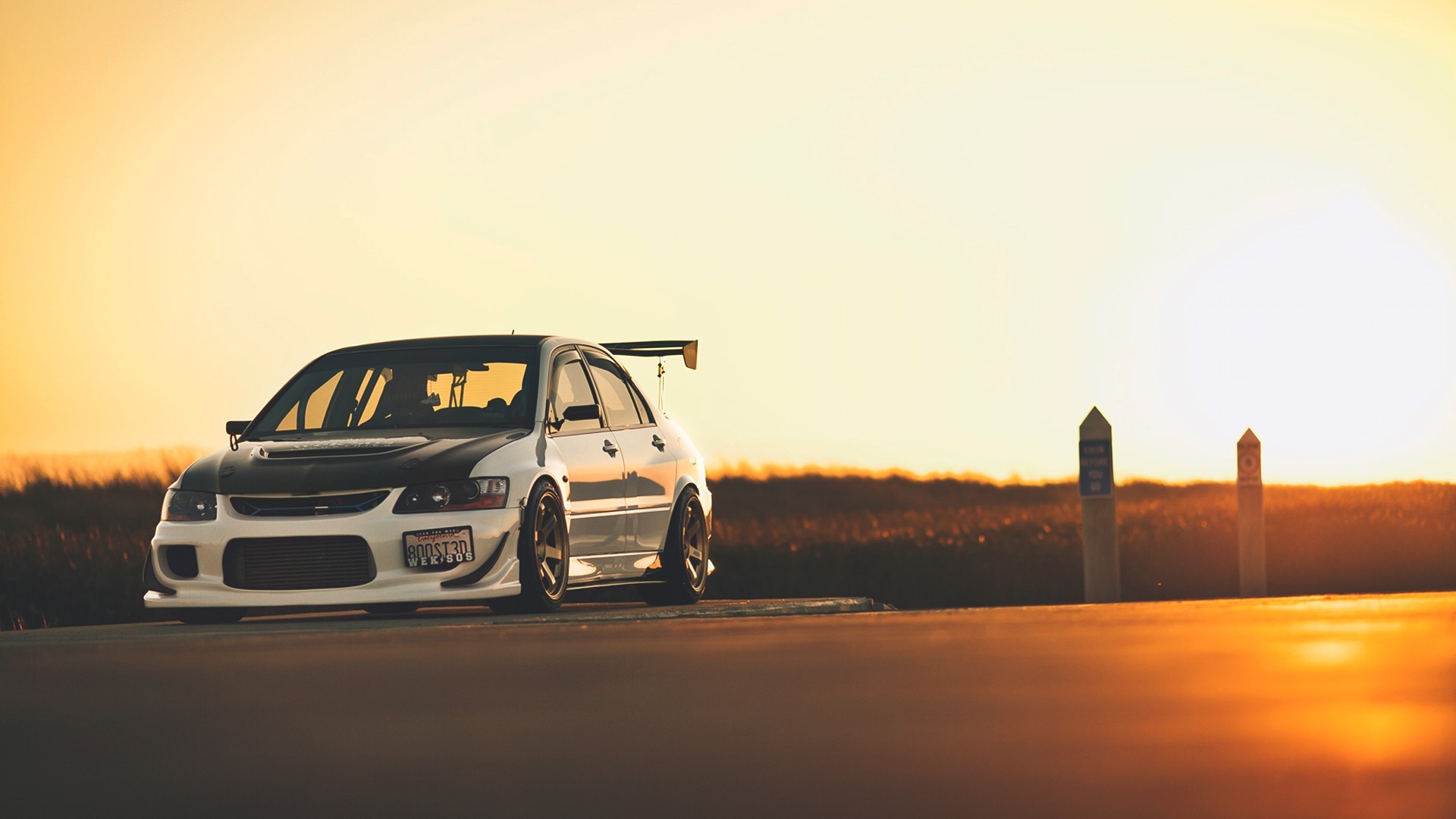 Mitsubishi evo stands on the side of the road at sunset.