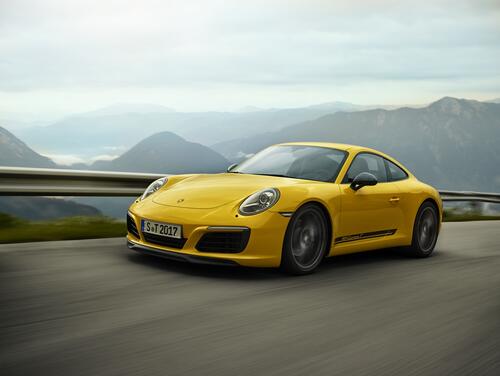 Porsche 911 carrera t желтого цвета едет по загородной дороге