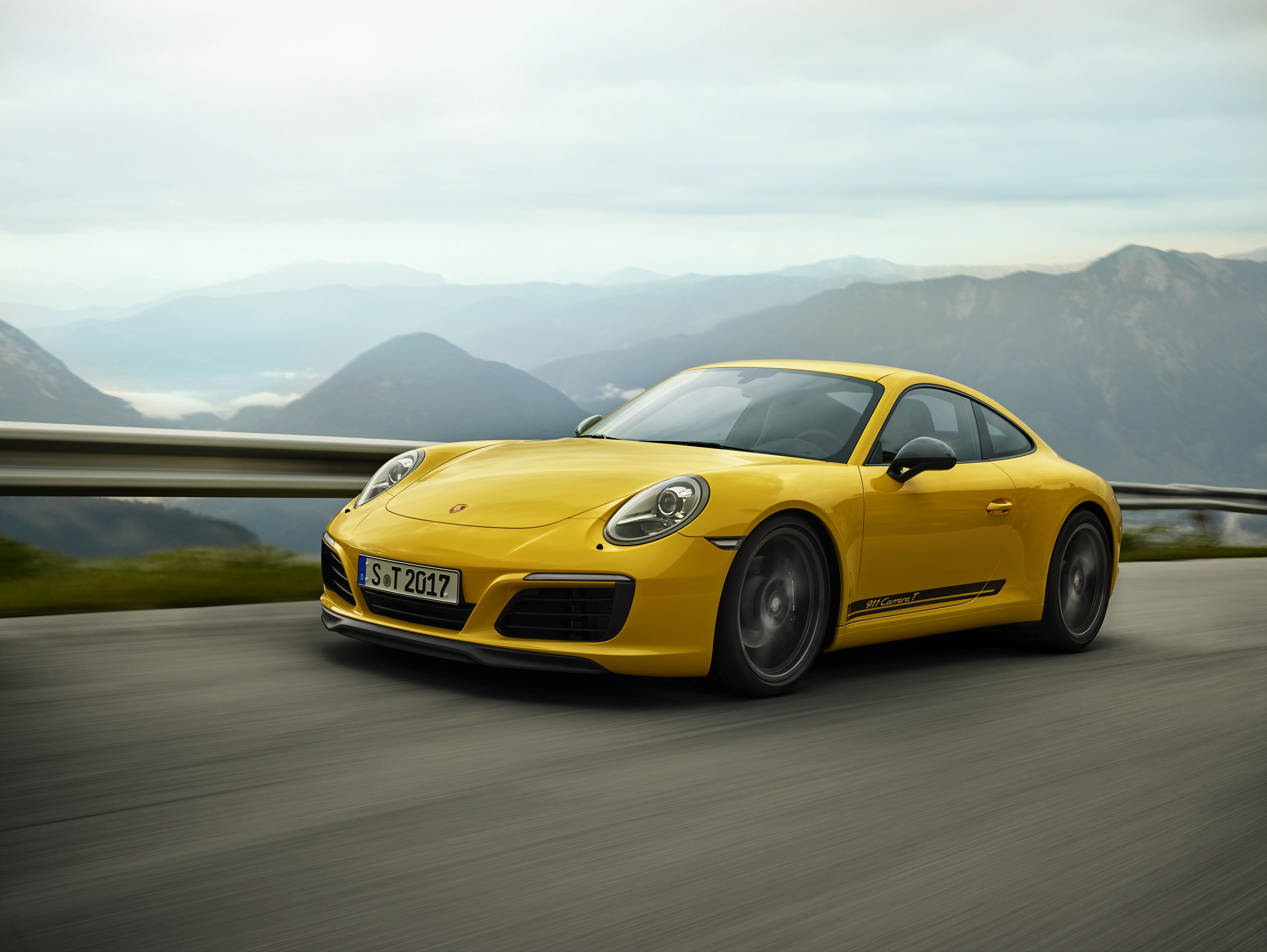 Бесплатное фото Porsche 911 carrera t желтого цвета едет по загородной дороге