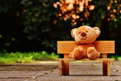 A teddy bear sitting on a bench.