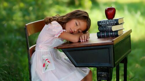 Девочка спит за рабочим столом
