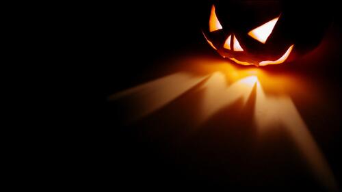 A Halloween pumpkin emits light in the darkness