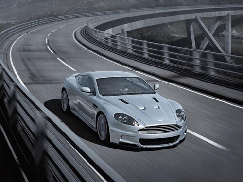 The Aston Martin Vanquish is driving on a country track.