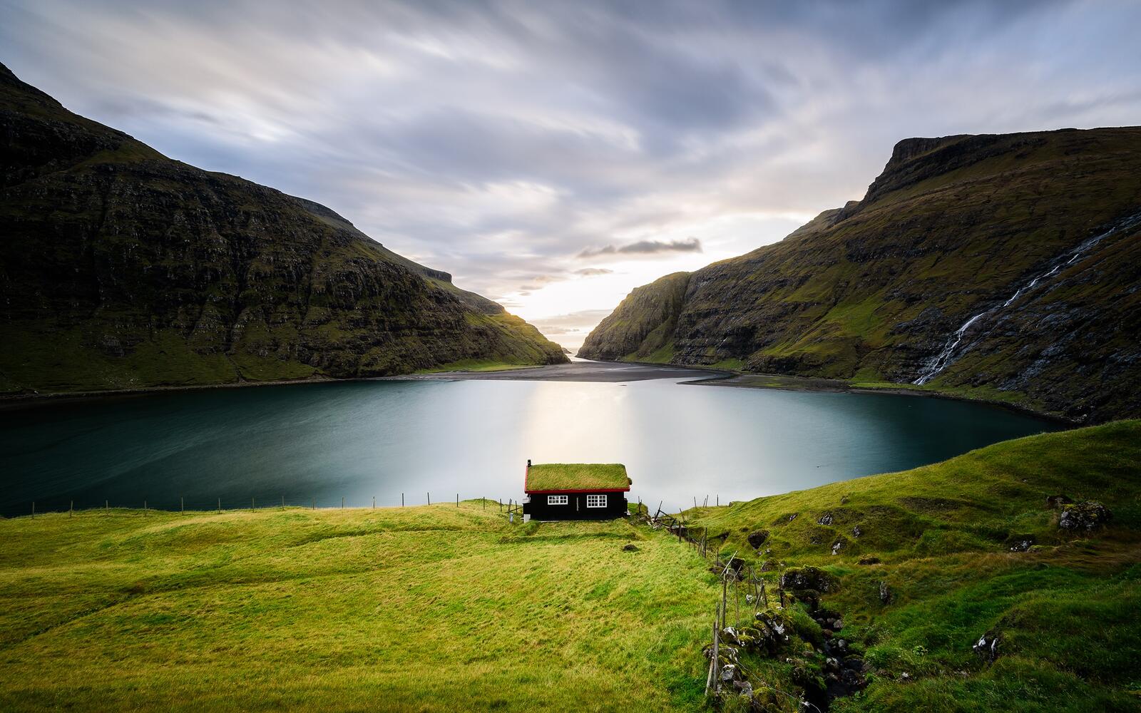 Free photo A lonely lakeside cottage with green grass on the roof