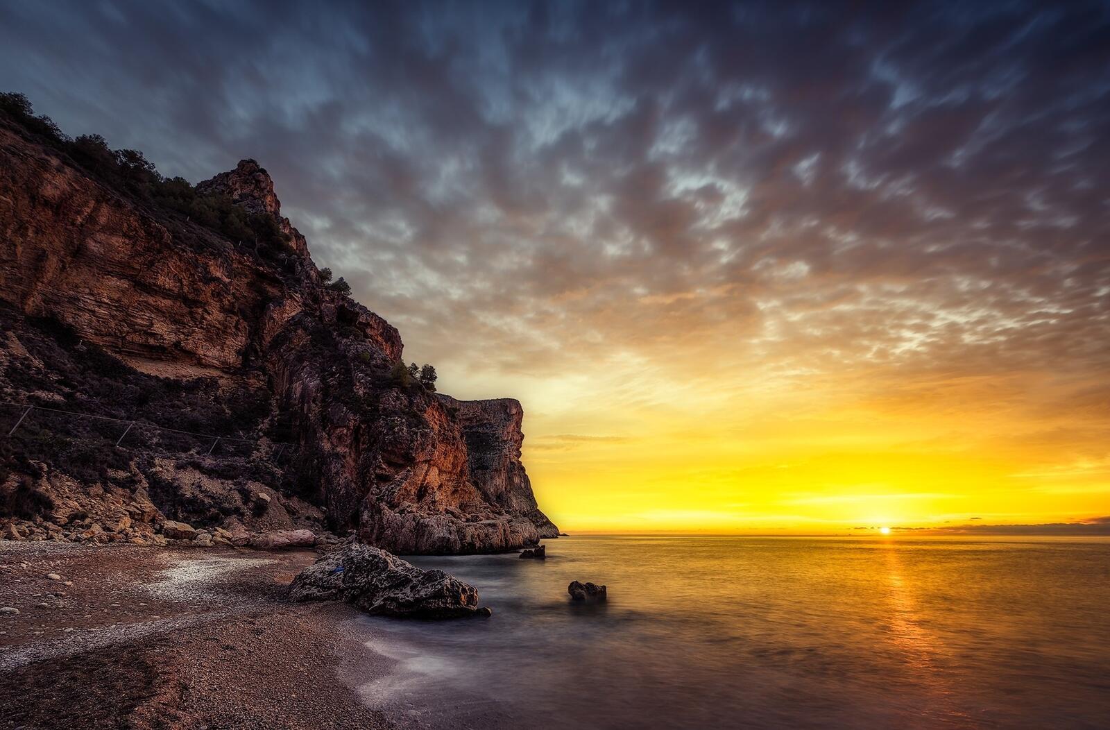 Бесплатное фото Закат на берегу моря у большой скалы
