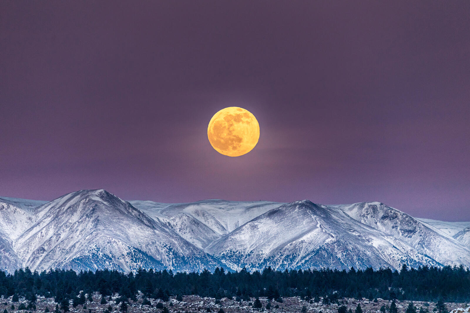 Free photo The yellow moon over the snowy mountains