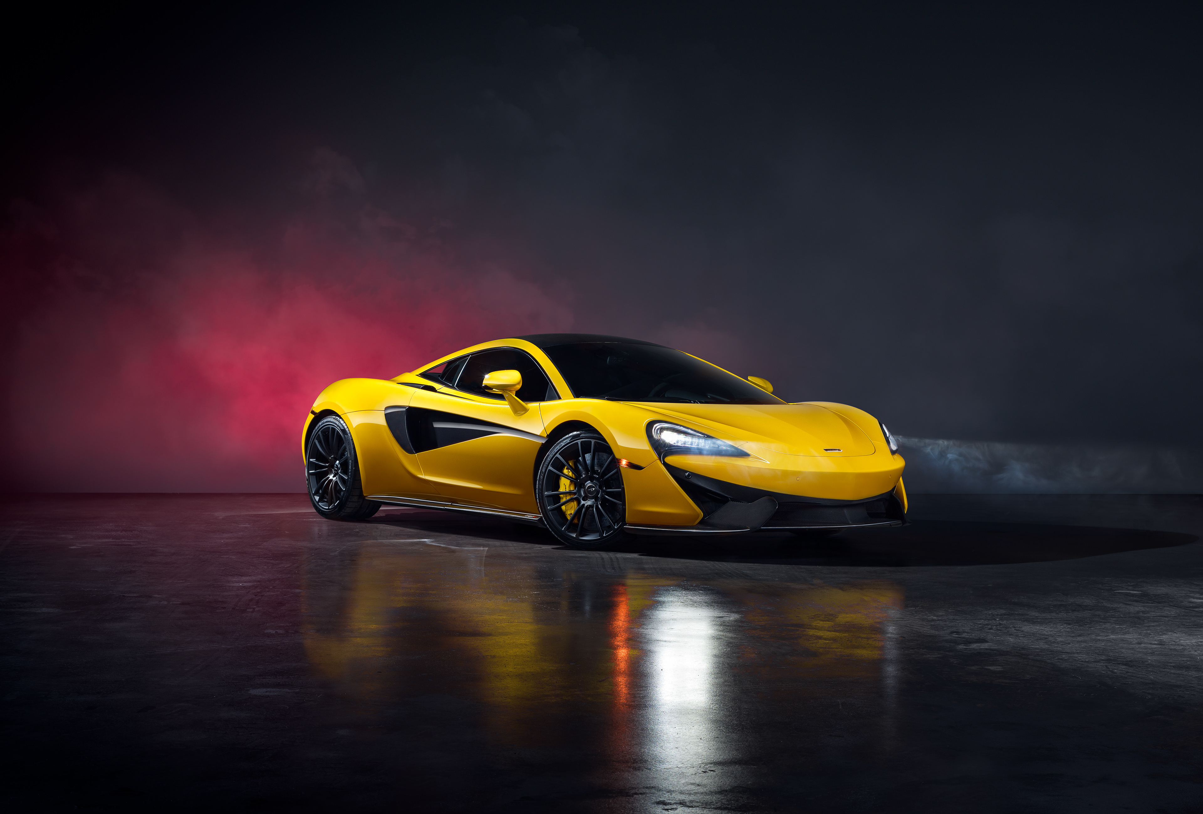 Free photo A yellow Mclaren 570S Spider in a black smoky room.