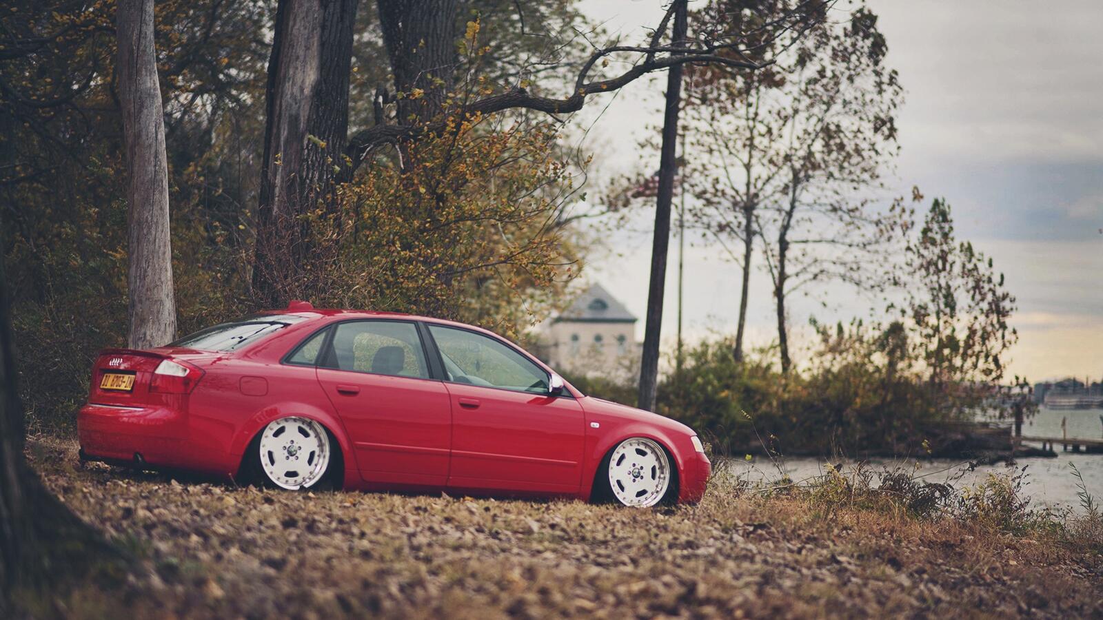 Бесплатное фото Заниженная Audi a4 красного цвета стоит на опавших листьях