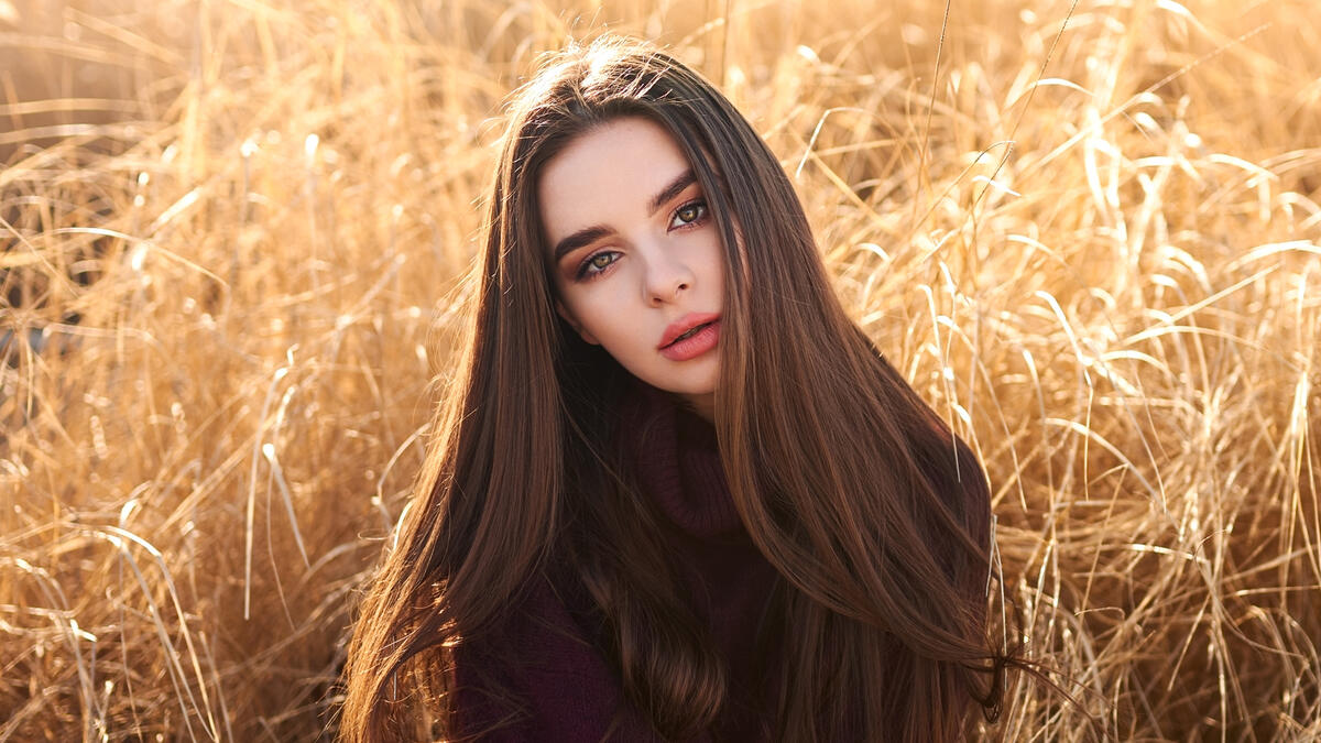 Beautiful dark-haired girl on the background of tall grass