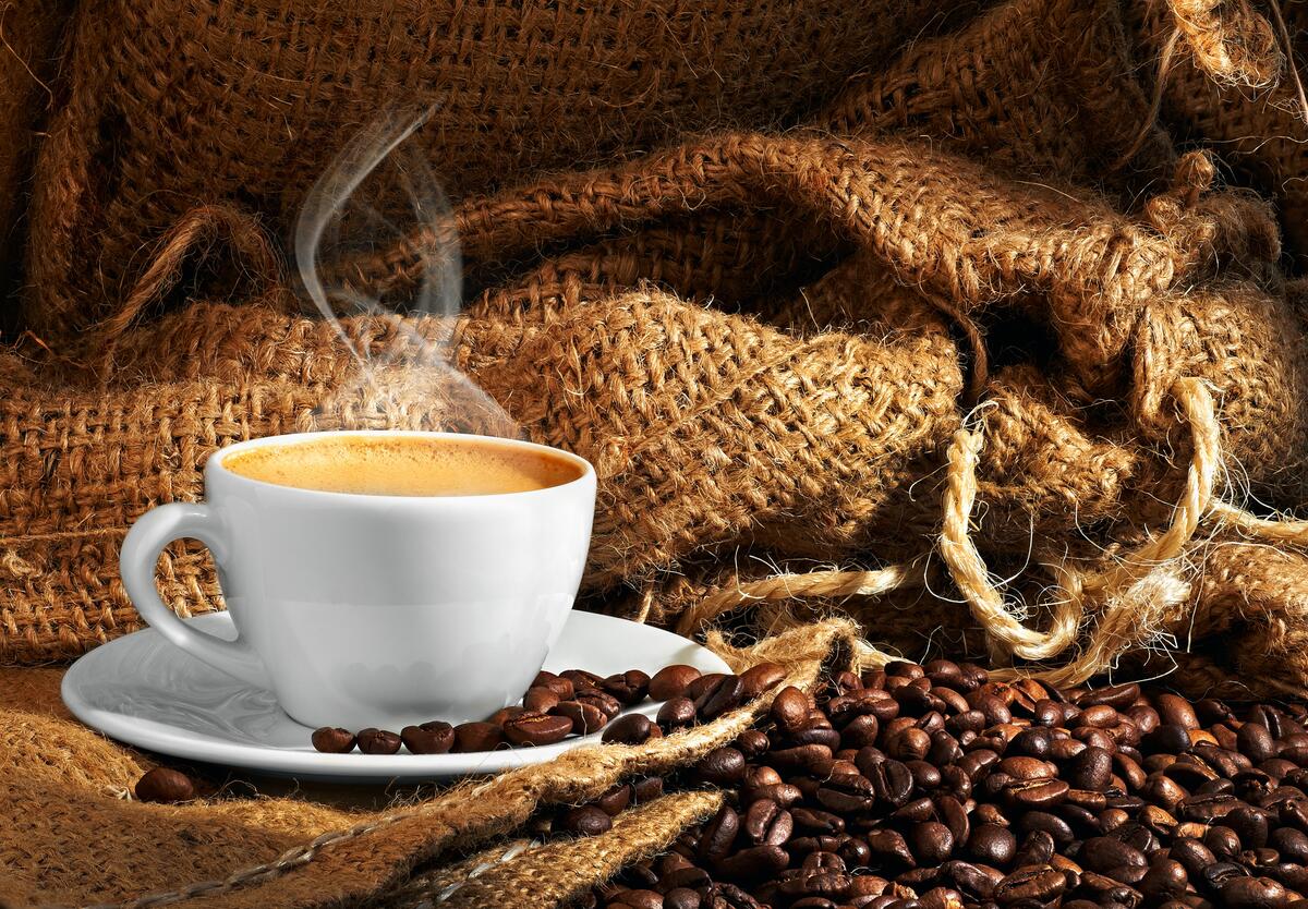 Чашка горячего кофе стоит у мешка с зернами