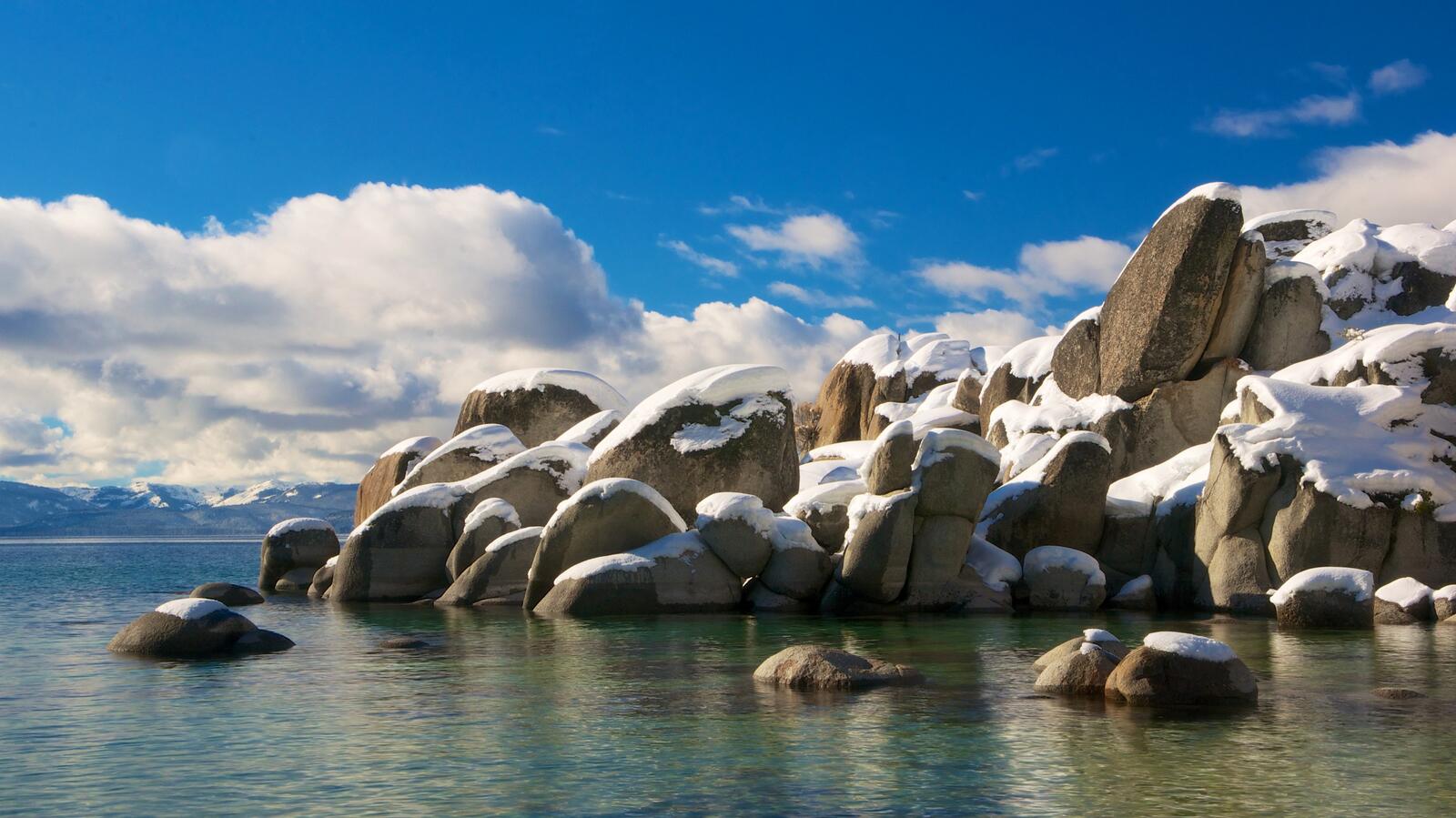 Бесплатное фото Снежные шапки на морских камнях