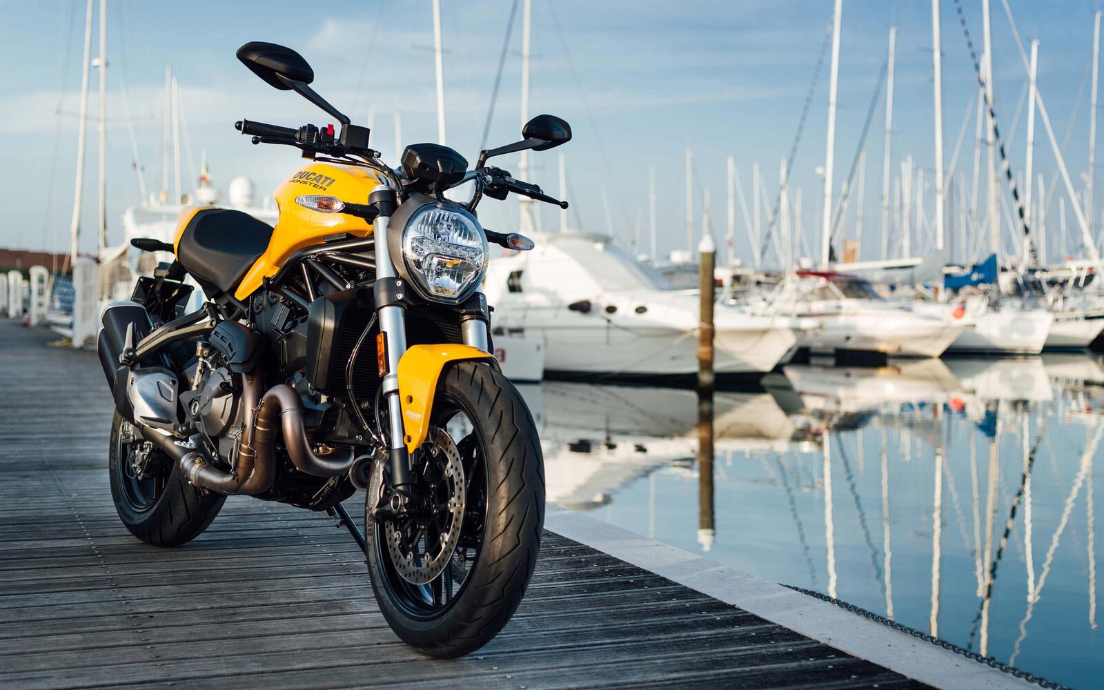Free photo Ducati monster 821 in yellow stands on a bridge by the water