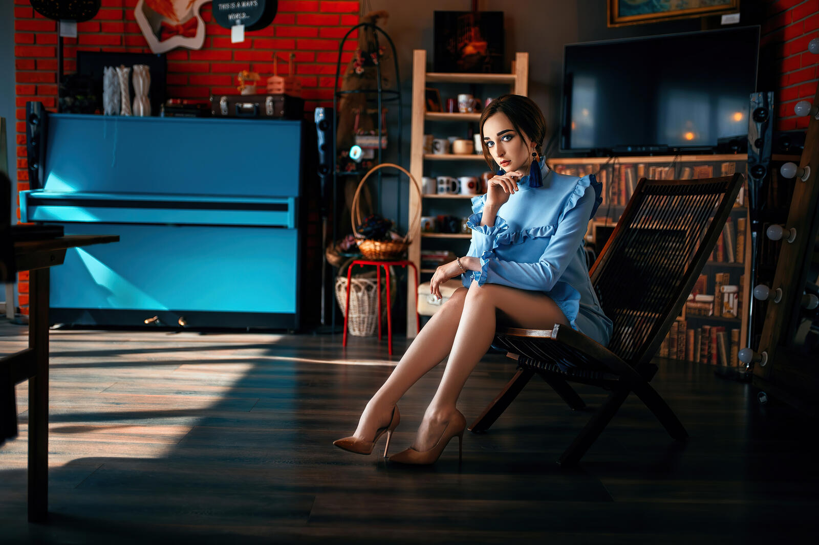 Бесплатное фото Молодая темноволосая девушка в голубом платье сидит на кресле качалке