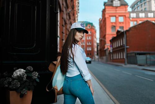 A girl in jeans and a baseball cap walks around town