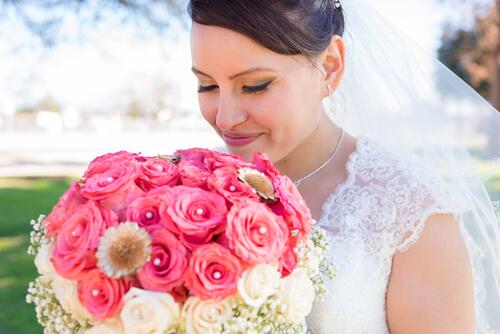 A girl in a wedding dress with a big bouquet of pink roses