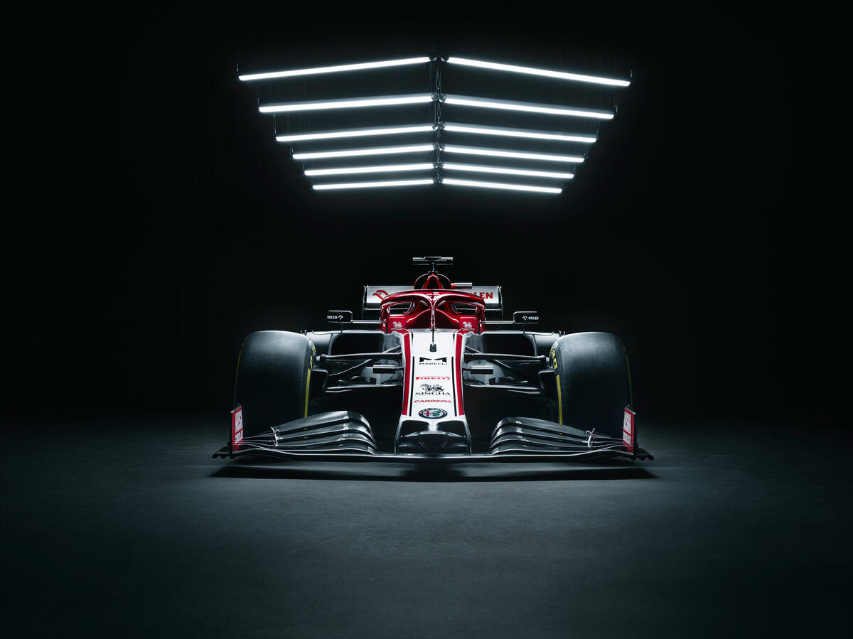 The Formula 1 is in a dark garage under a lamp.