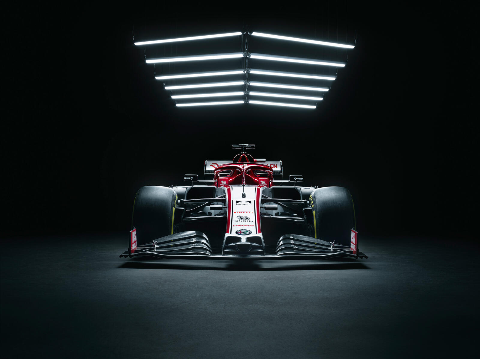 Бесплатное фото Формула 1 стоит в темном гараже под лампой
