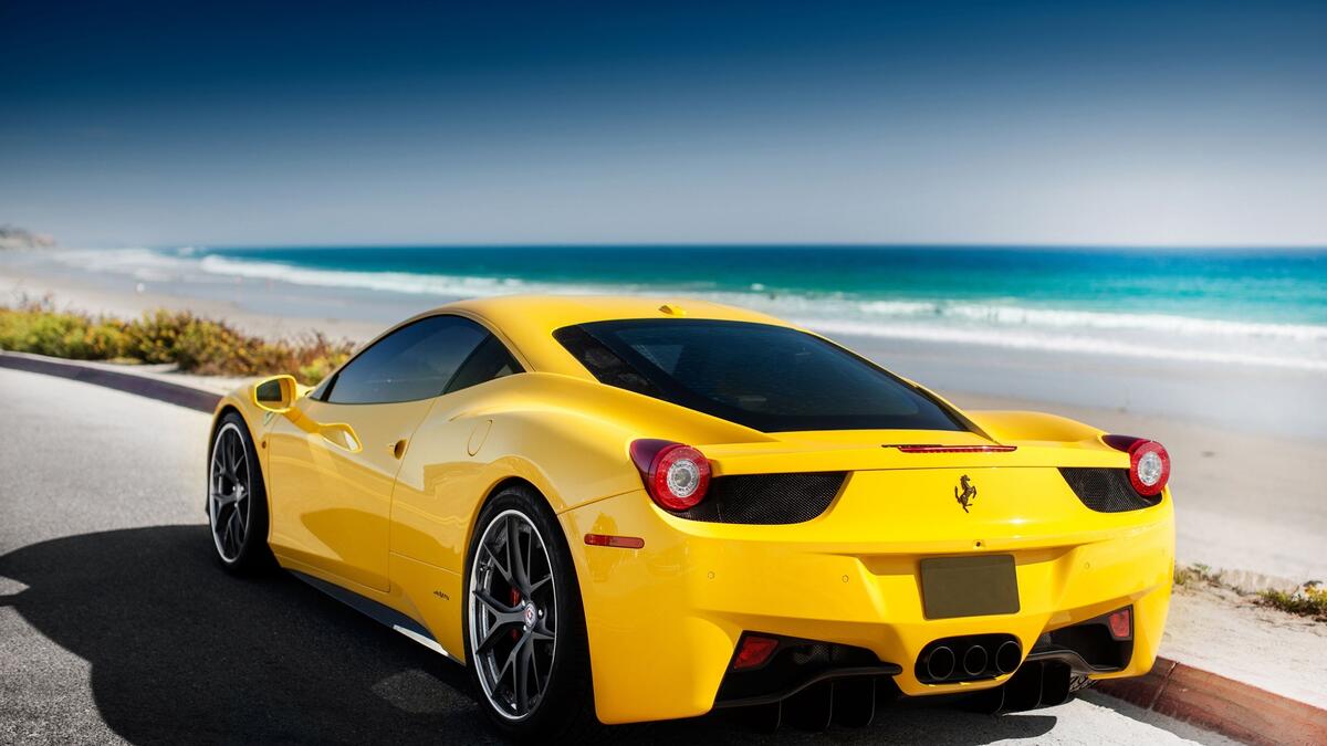 A yellow Ferrari 458 against the sea.