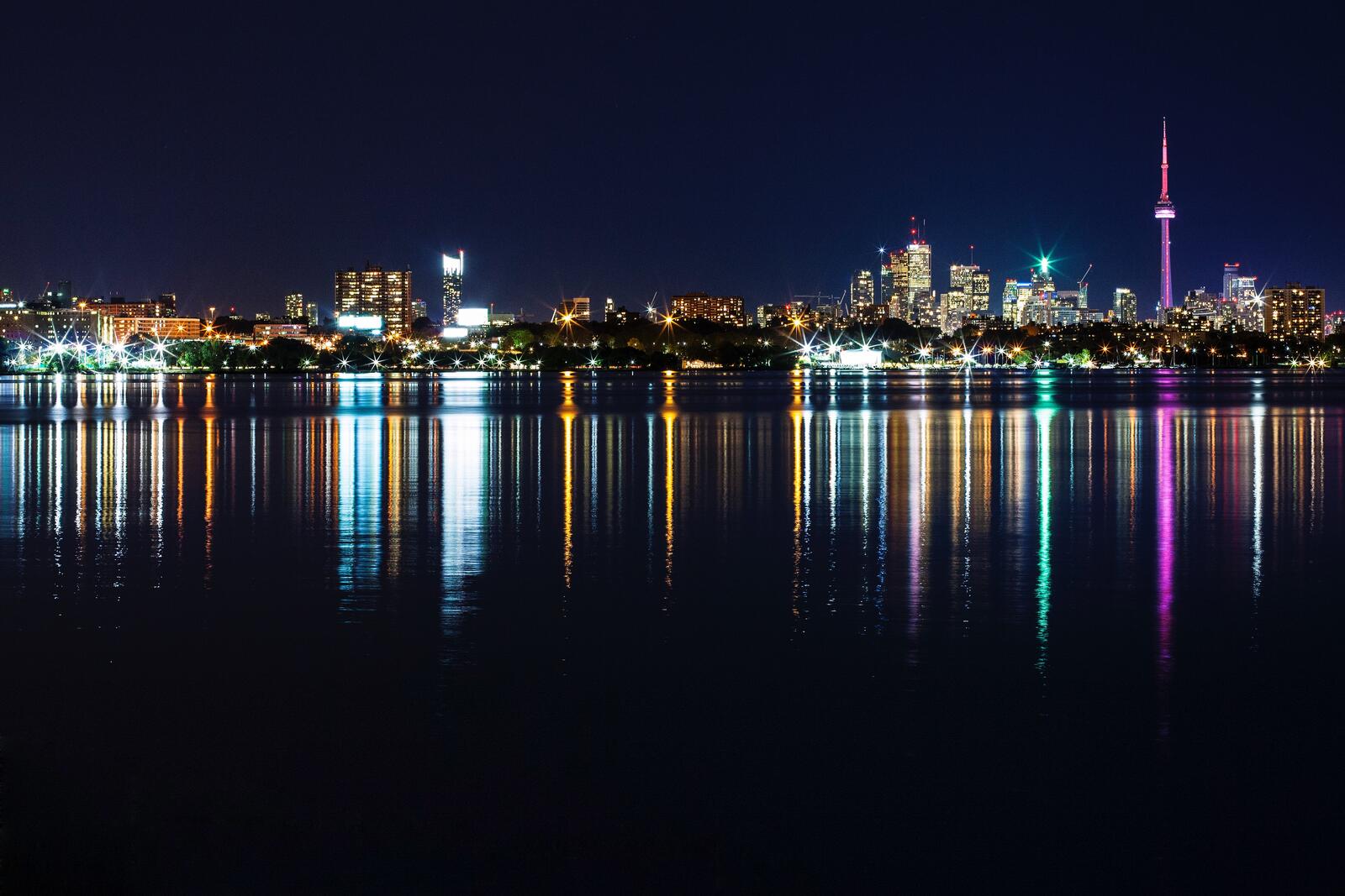 免费照片夜晚摩天大楼的灯光倒映在水面上