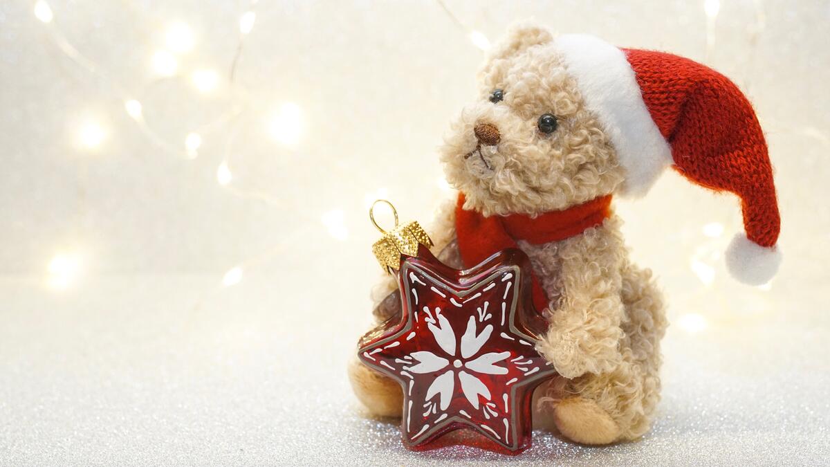 Плюшевый медведь в новогодней шапке с новогодней игрушкой