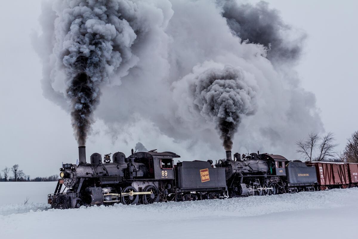 A steam locomotive driving through a snowy field