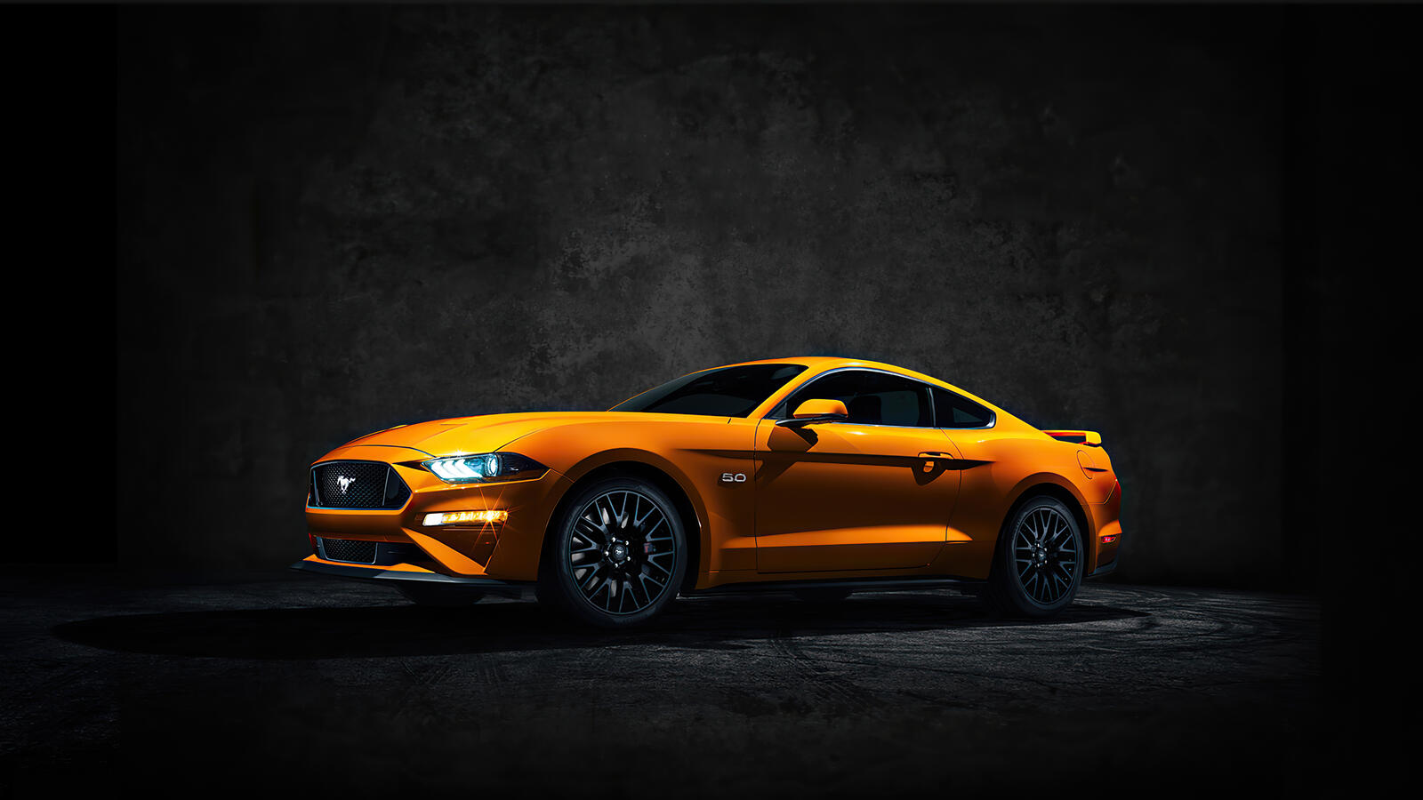 Free photo A yellow Ford Mustang in a darkened room.