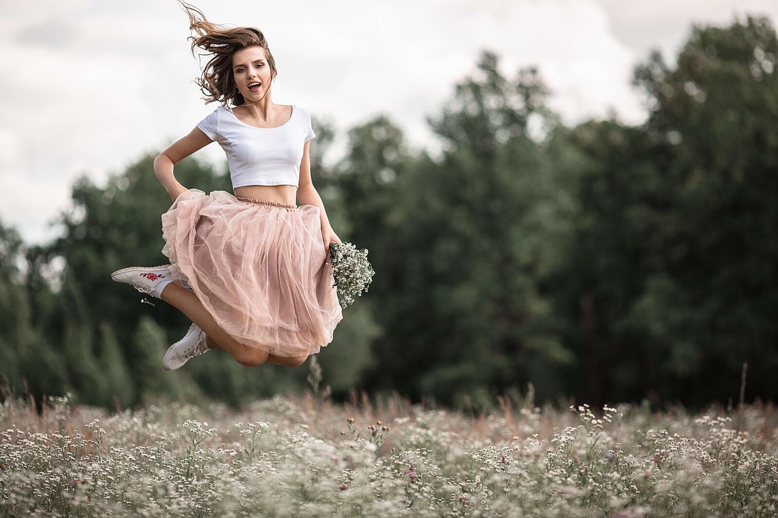 Бесплатное фото Девушка сфотографированная в прыжке на цветочном поле