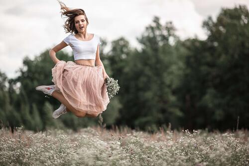 Девушка сфотографированная в прыжке на цветочном поле