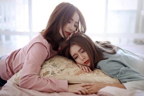Two Asian girls sleeping on the same pillow