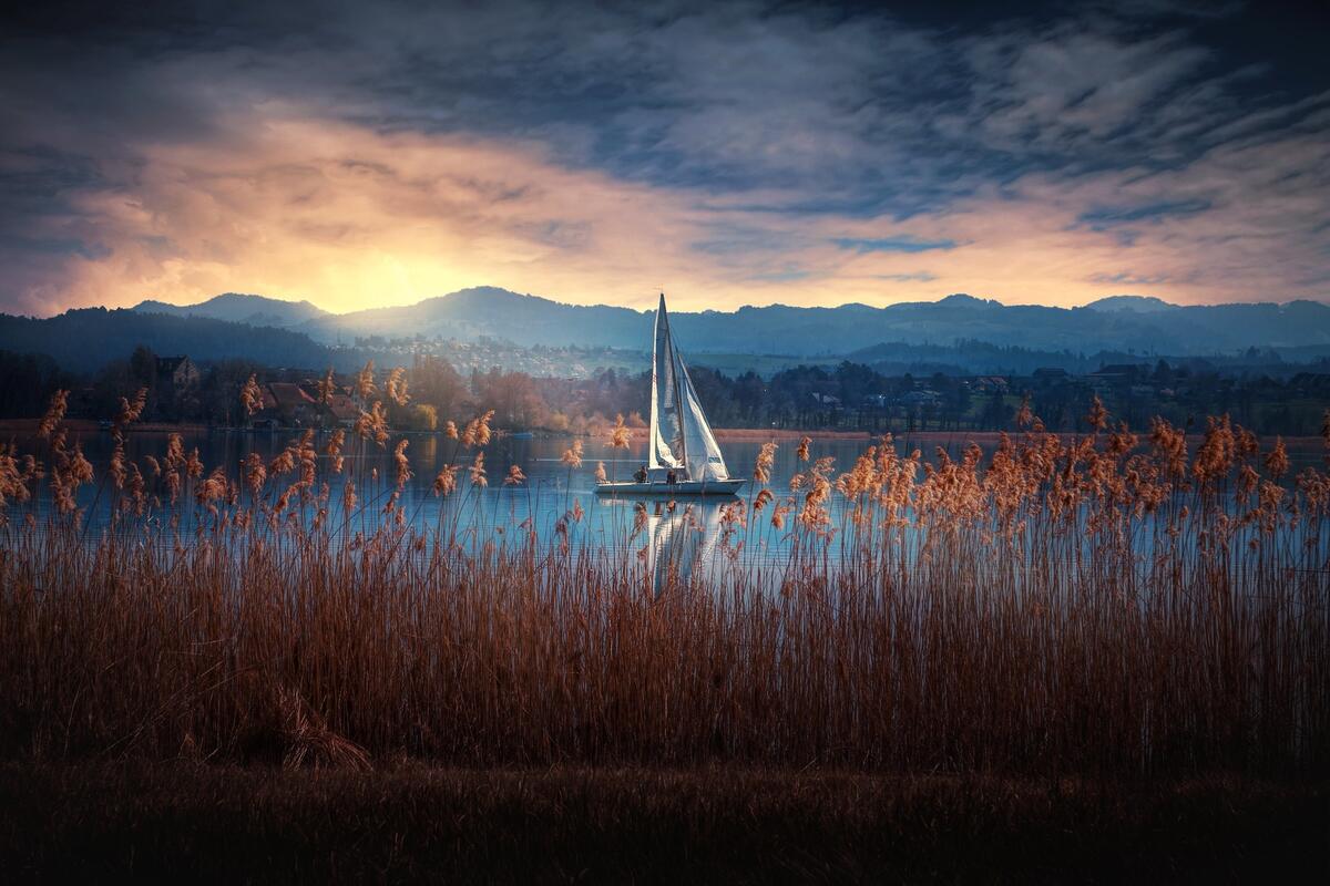 Одинокий парусник на озере во время заката
