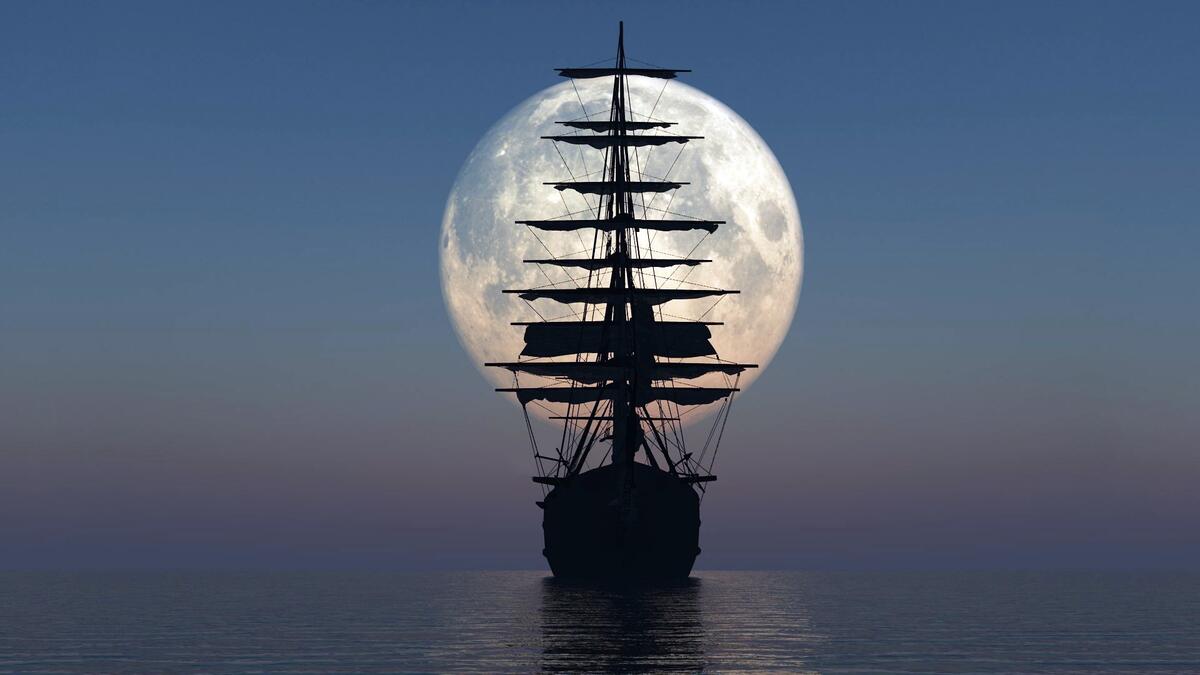 The silhouette of a large sailing ship against the moon.