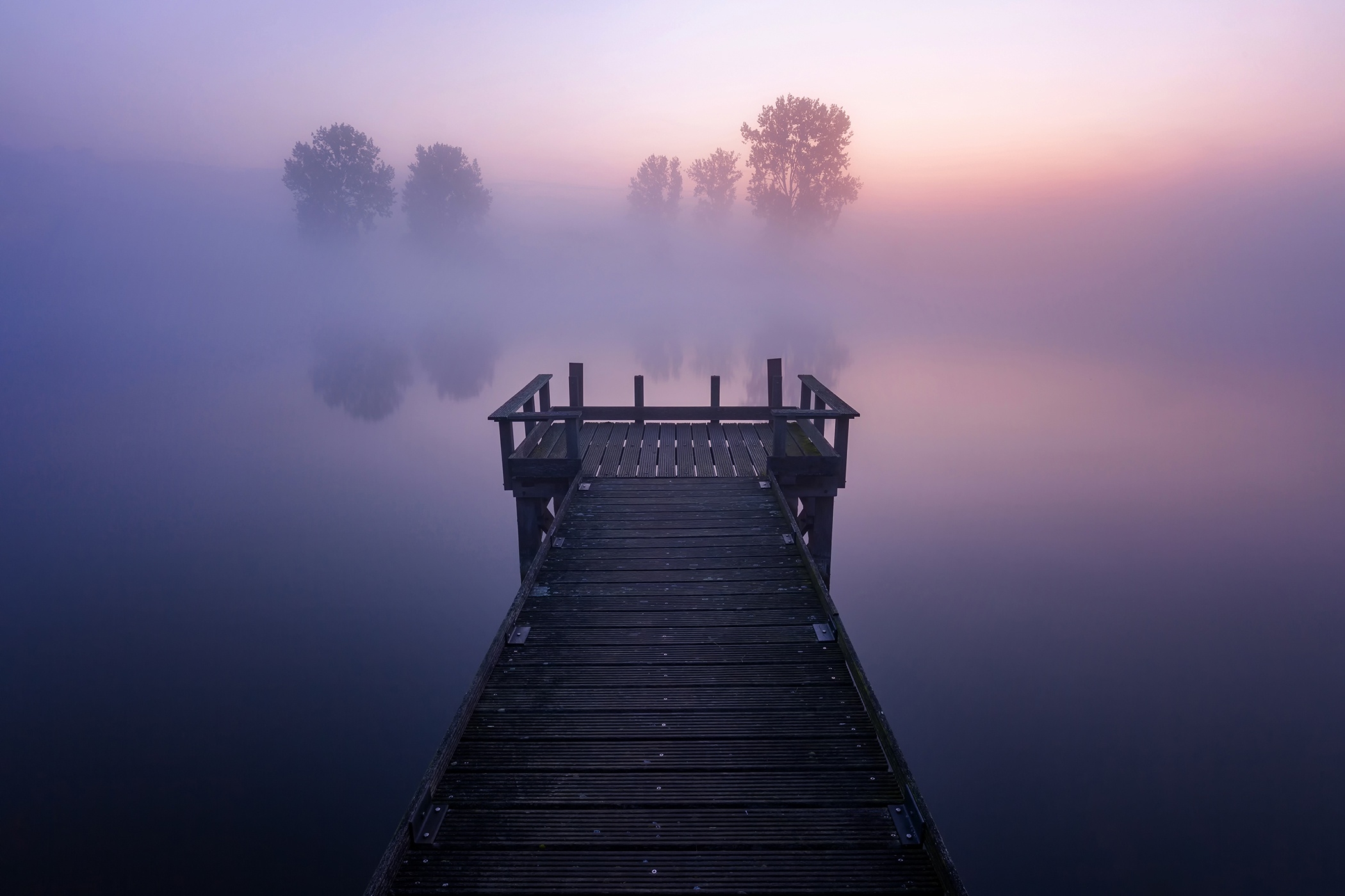 Wooden bridge on the lake with morning mist