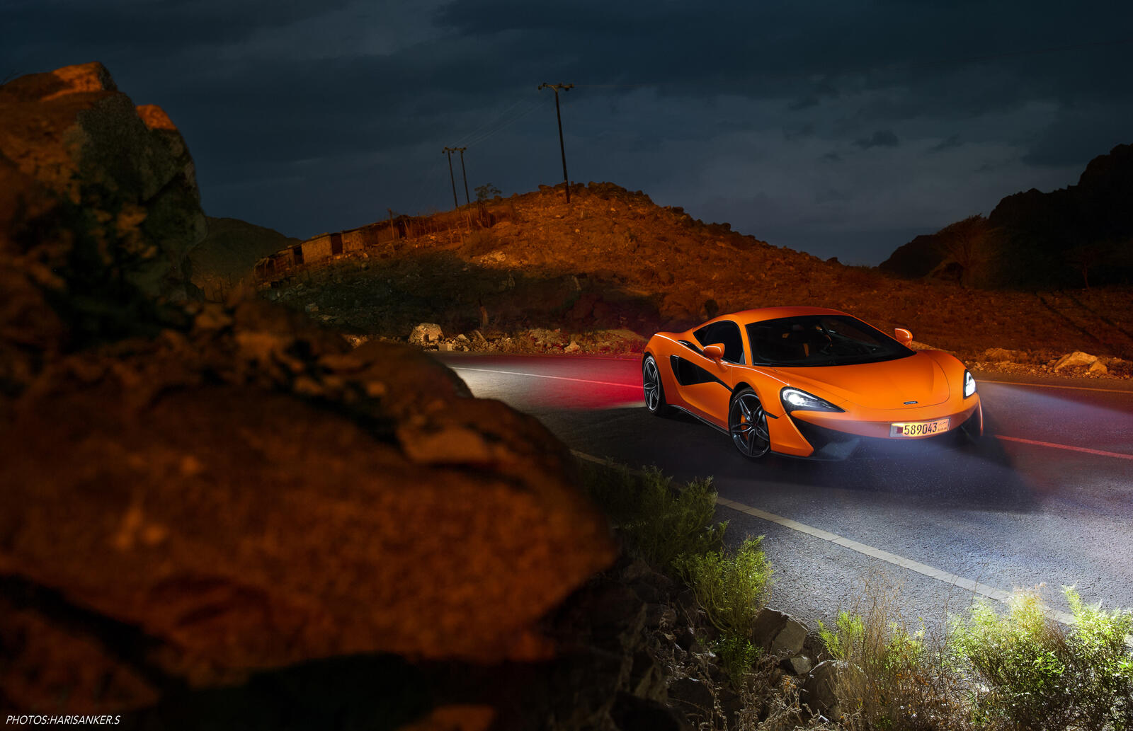 Free photo An orange-colored Mclaren on the road at night.