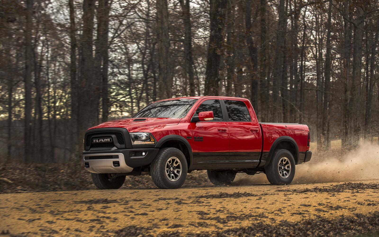 Free photo A red-colored Dodge Ram driving down a forest road