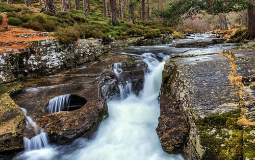 A forest waterfall on a river in the woods of Scotland