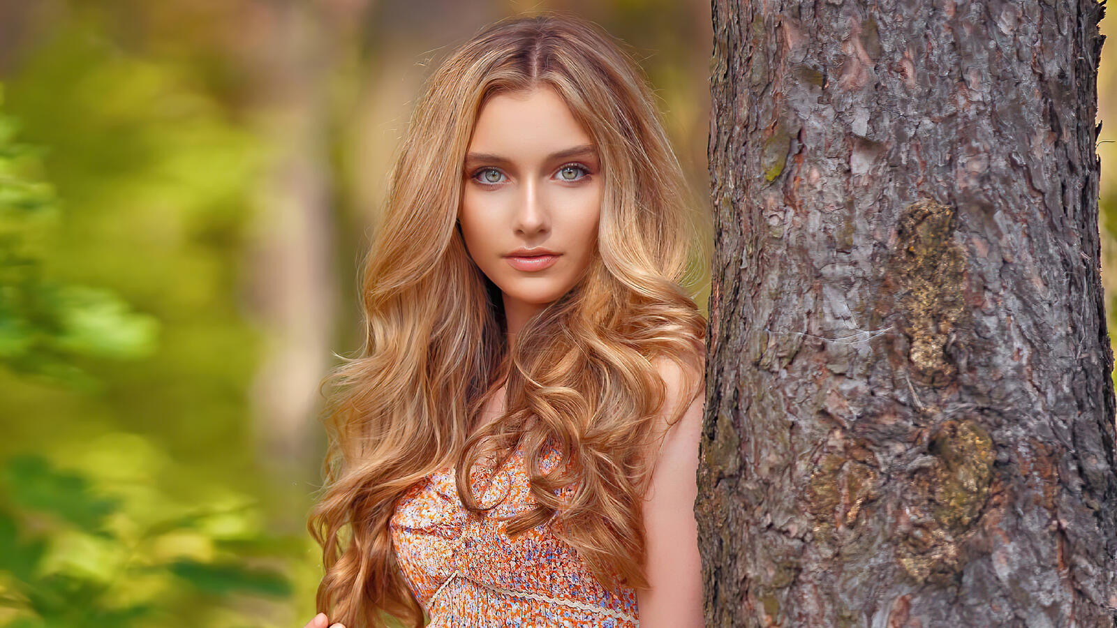 Free photo Blonde-haired Alexandra Lenarchuk stands by a tree