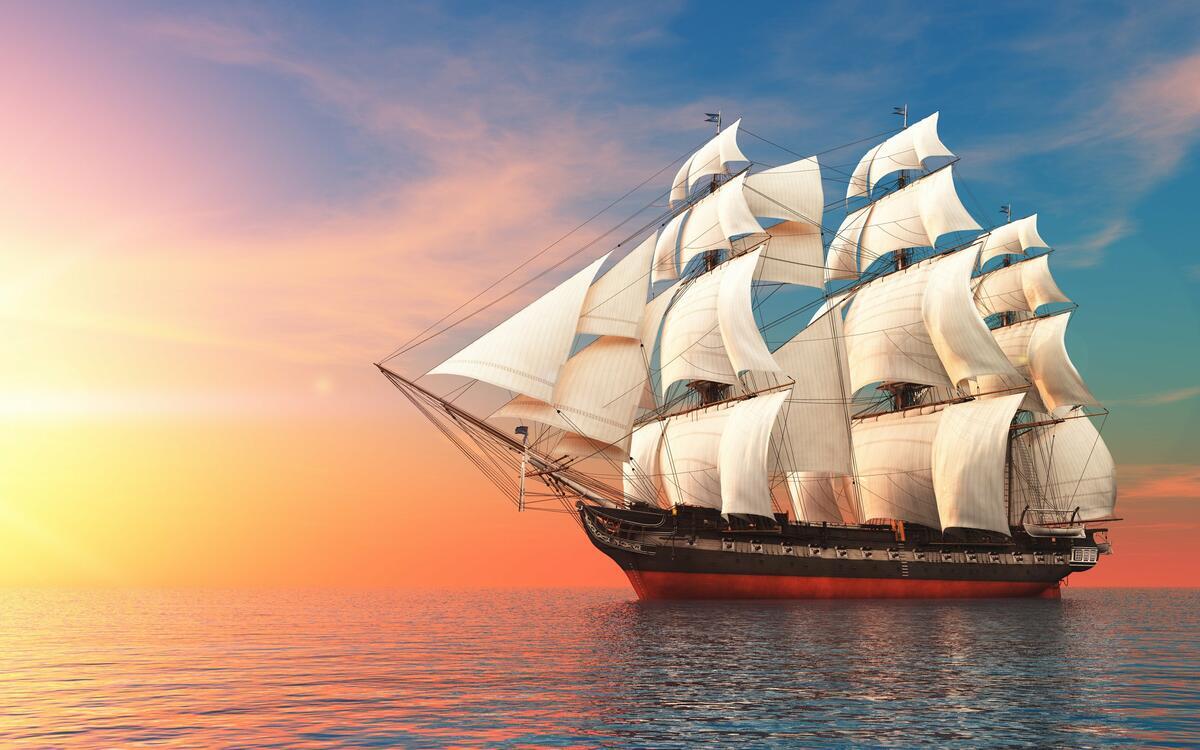 A big ship with white sails at sunset.