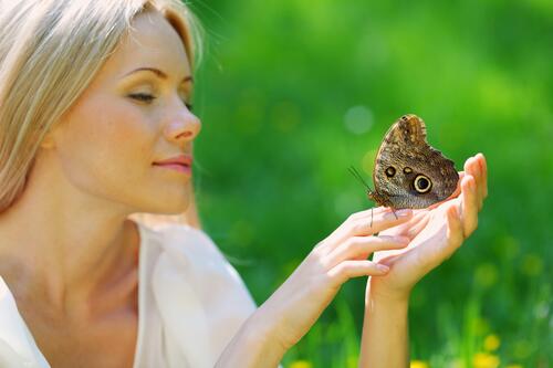 A woman holding a butterfly on her arm