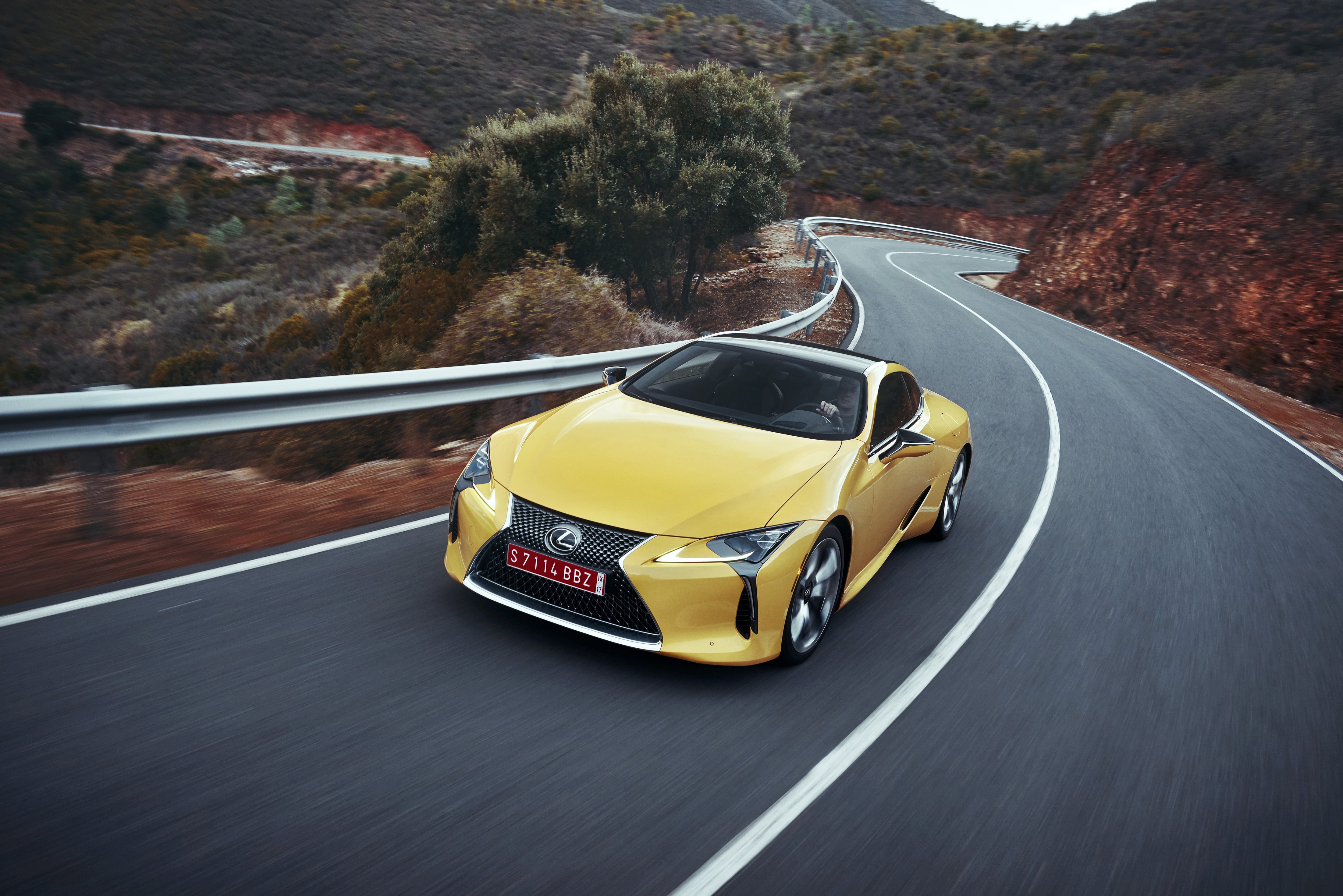A yellow lexus lc 500 on a country road.