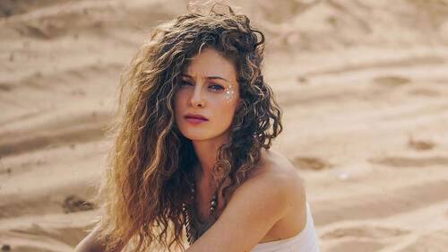 Curly-haired Efrat Dor sits on the sand