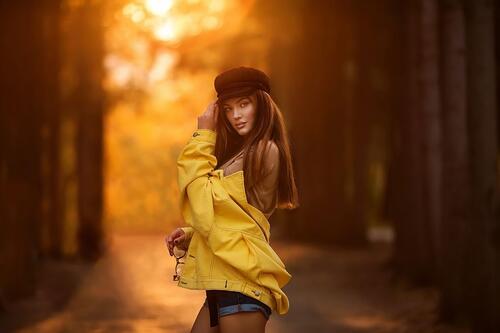 Dark-haired girl in yellow jacket at sunset
