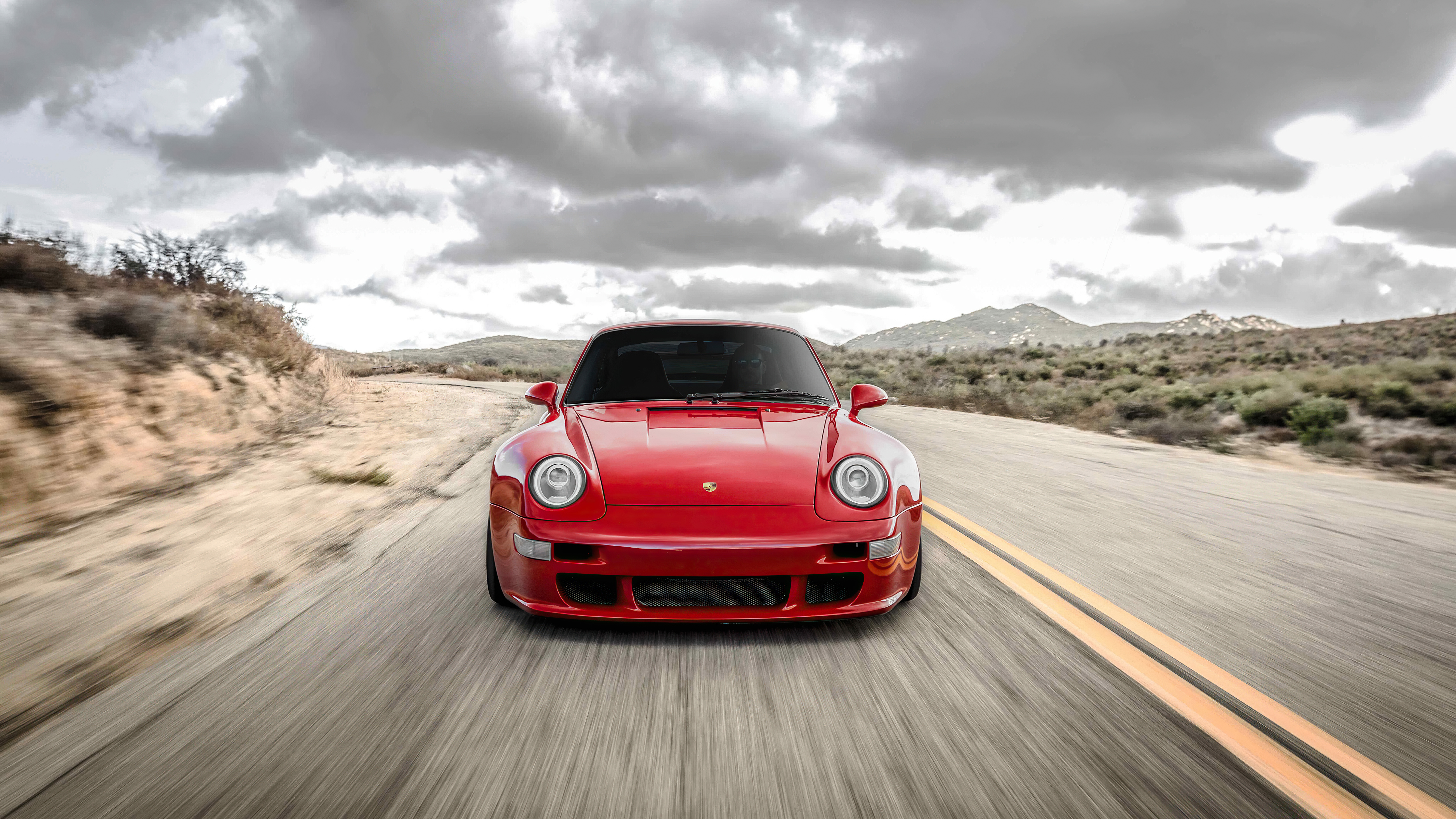 Красный Porsche 911 едет по трассе вид спереди