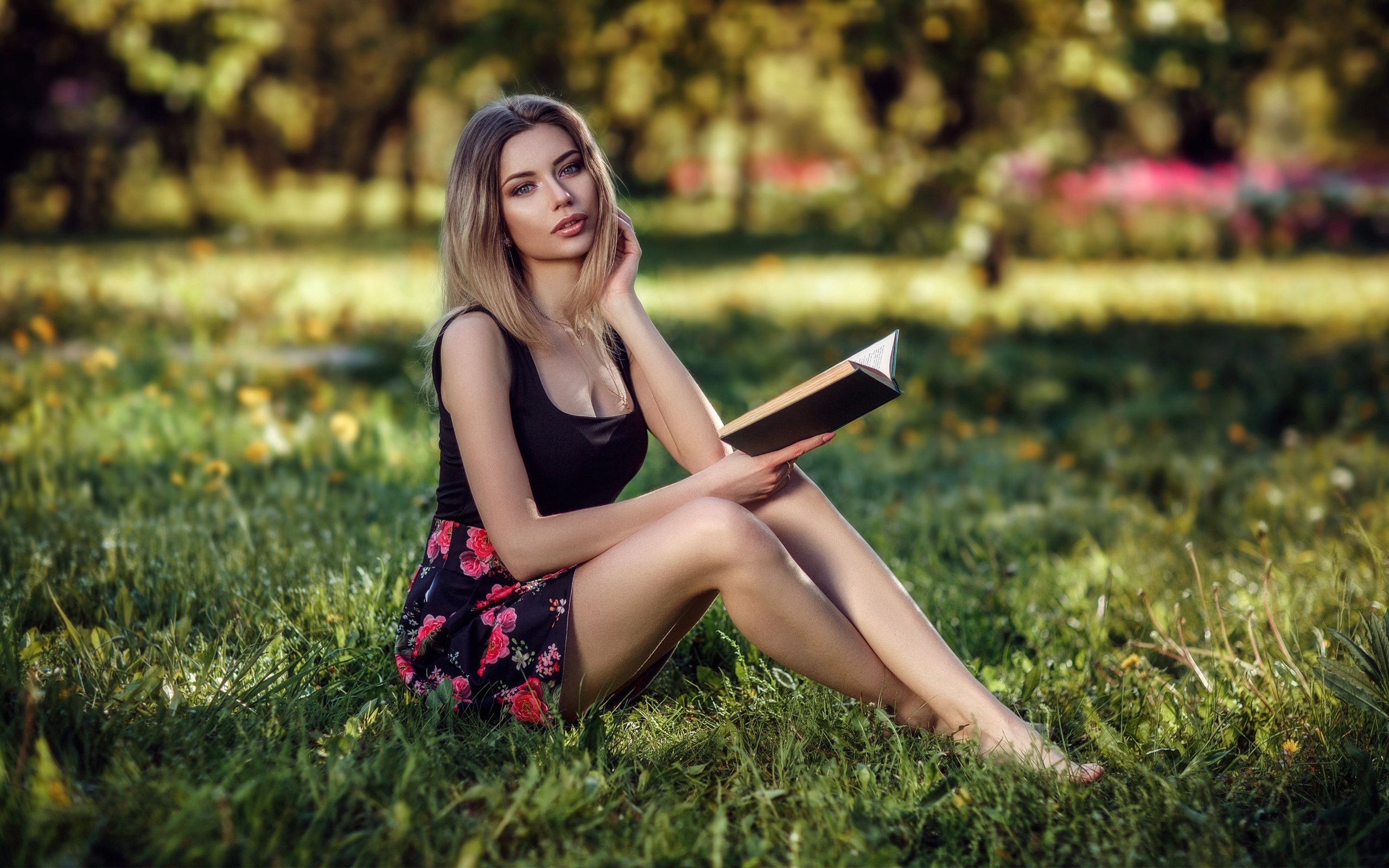 Девушка в парке читает книгу сидя на траве