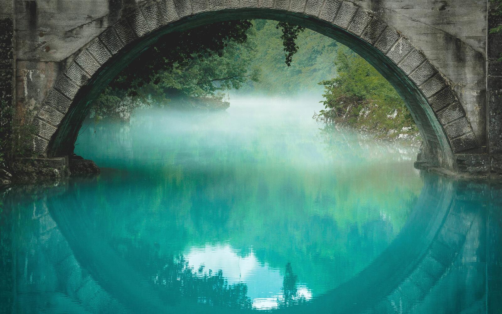 Free photo A stone bridge over a river with blue water