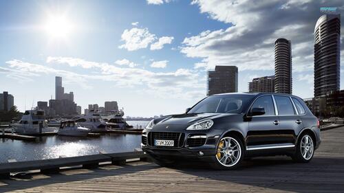 An old Porsche Cayenne with the city as a backdrop.