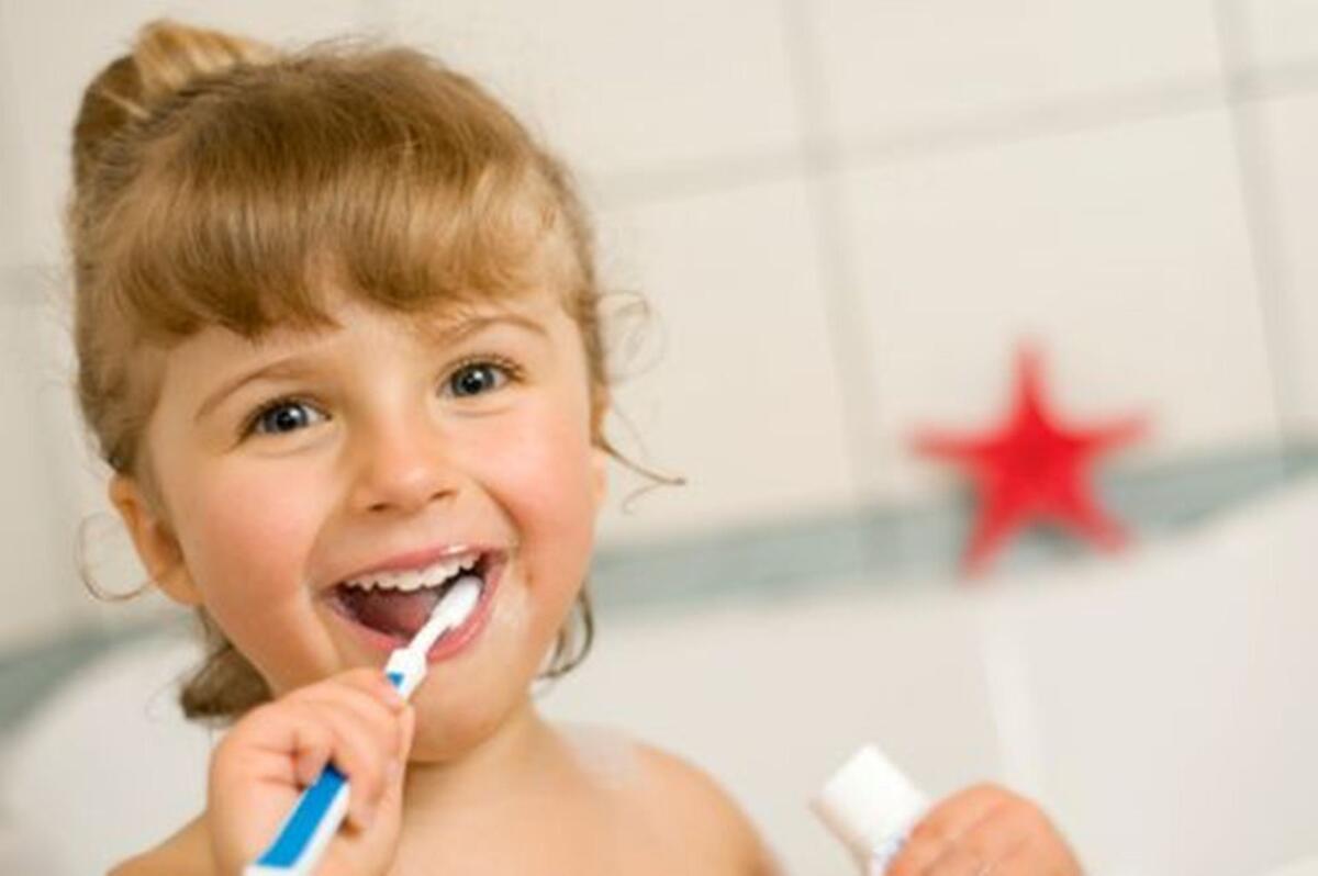 A little girl brushing her teeth and smiling