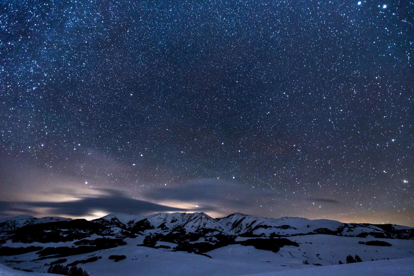 Free photo Evening starry sky over mountains covered with snow