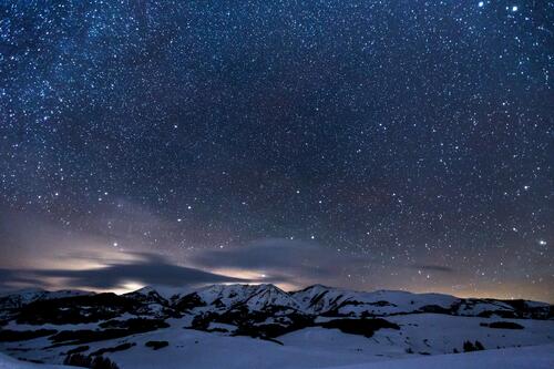 Вечернее звездное небо над горами покрытыми снегом