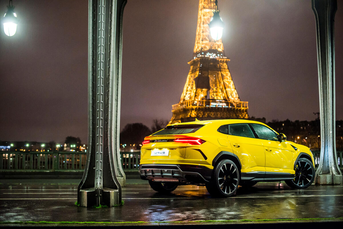 A yellow Lamborghini Urus against the backdrop of the Eiffel Tower