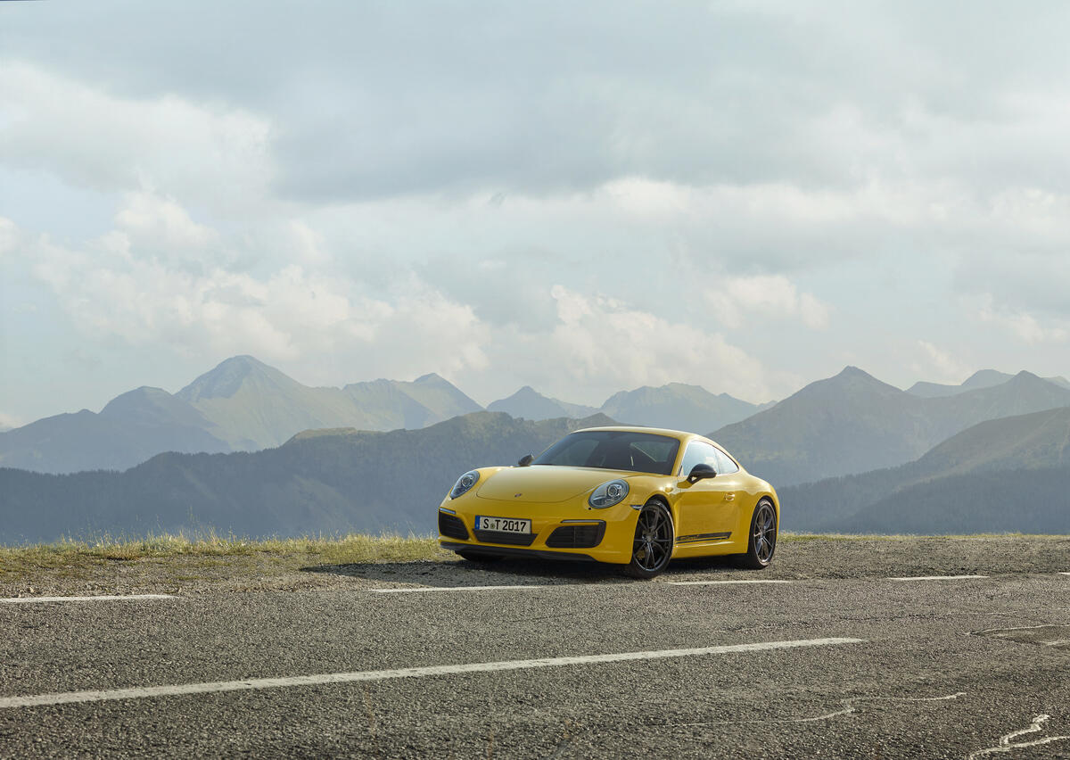 Желтый Porsche 911 стоит на обочине на загородной трассе
